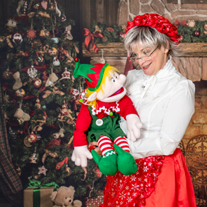 An image of Santa Sue holding a puppet elf